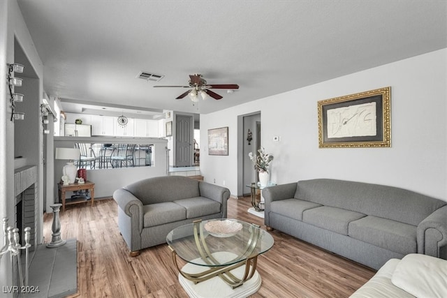 living room featuring a fireplace, hardwood / wood-style flooring, and ceiling fan