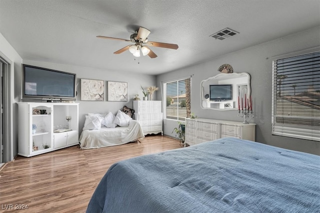 bedroom with ceiling fan, hardwood / wood-style flooring, and a textured ceiling