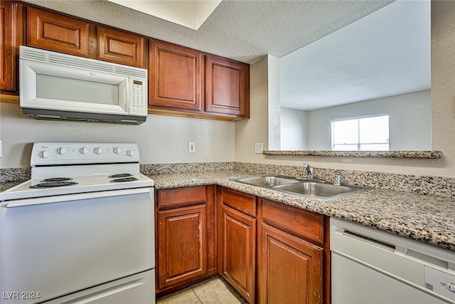 kitchen featuring light stone counters, sink, white appliances, and light tile patterned flooring