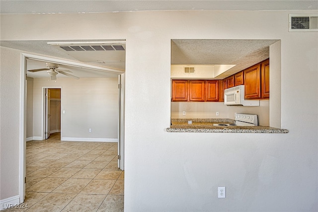 kitchen featuring white appliances, a textured ceiling, light tile patterned floors, light stone countertops, and ceiling fan