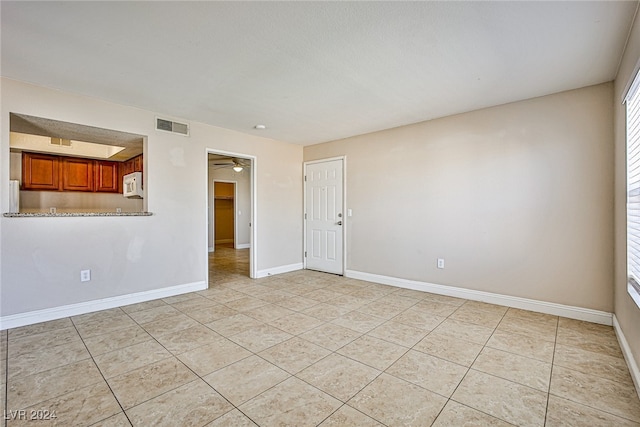 empty room featuring ceiling fan, light tile patterned floors, and a healthy amount of sunlight