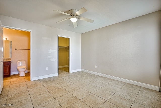 unfurnished bedroom featuring a walk in closet, a closet, light tile patterned floors, connected bathroom, and ceiling fan