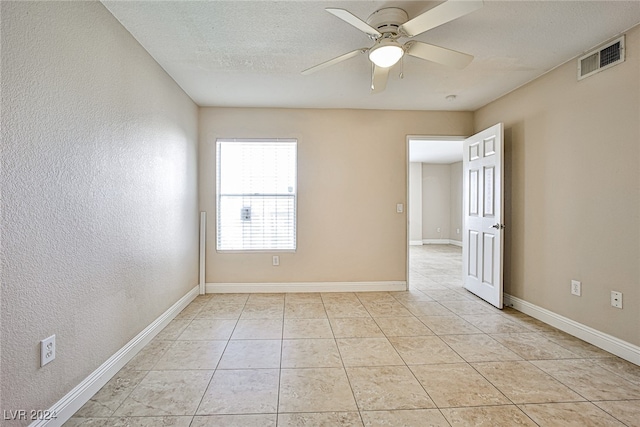 tiled empty room with ceiling fan and a textured ceiling