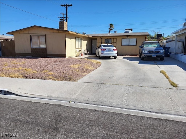 single story home featuring concrete driveway and a chimney