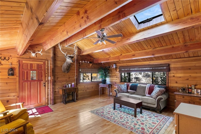 living room with hardwood / wood-style flooring, wooden walls, lofted ceiling with skylight, wooden ceiling, and ceiling fan