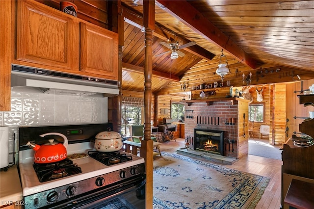 kitchen featuring black range, wooden walls, lofted ceiling with beams, a brick fireplace, and hardwood / wood-style floors