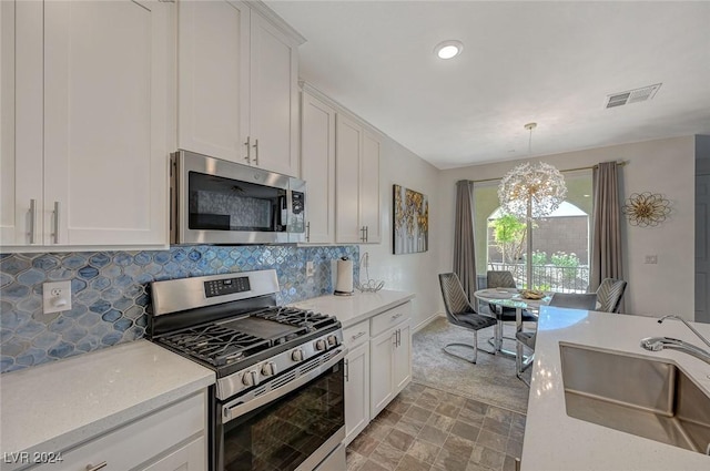 kitchen with tasteful backsplash, stainless steel appliances, sink, a notable chandelier, and white cabinets