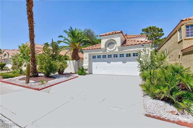 mediterranean / spanish-style house with a garage, fence, a tiled roof, driveway, and stucco siding