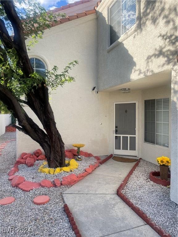 doorway to property featuring a tile roof and stucco siding