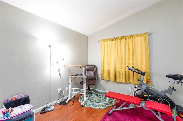 exercise room with lofted ceiling and hardwood / wood-style floors