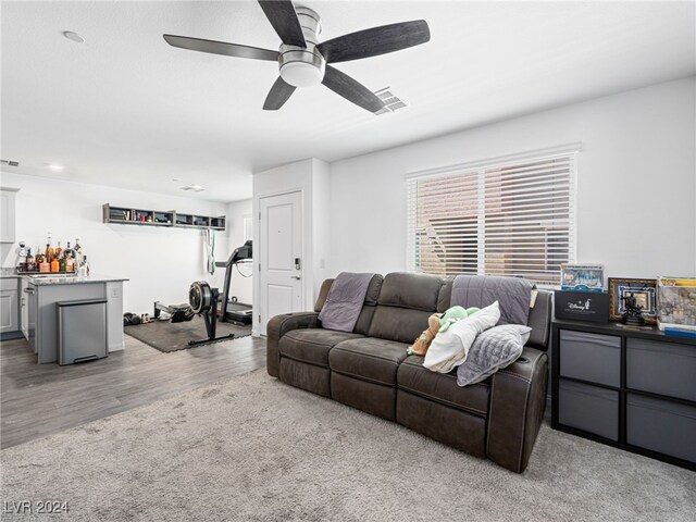 living room with light hardwood / wood-style flooring, bar area, and ceiling fan