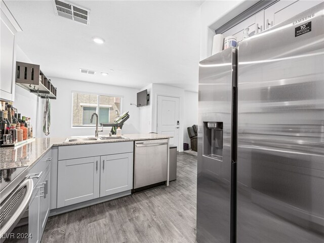 kitchen with light wood-type flooring, gray cabinets, stainless steel appliances, and sink