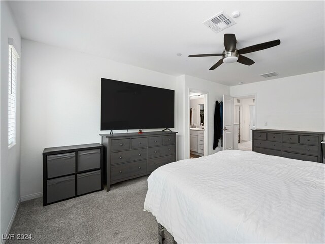 bedroom with light colored carpet, ensuite bathroom, and ceiling fan