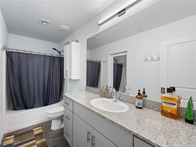 full bathroom featuring toilet, vanity, hardwood / wood-style flooring, a textured ceiling, and shower / tub combo