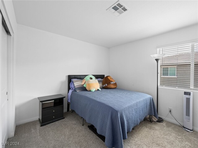 bedroom featuring a closet, heating unit, and carpet floors