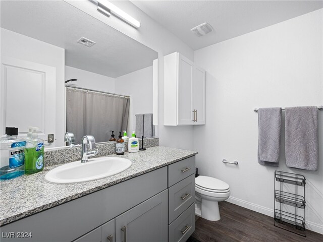 bathroom featuring toilet, hardwood / wood-style floors, vanity, a textured ceiling, and curtained shower