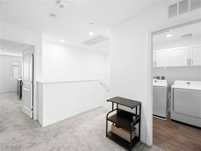 laundry room with independent washer and dryer, cabinets, and light colored carpet