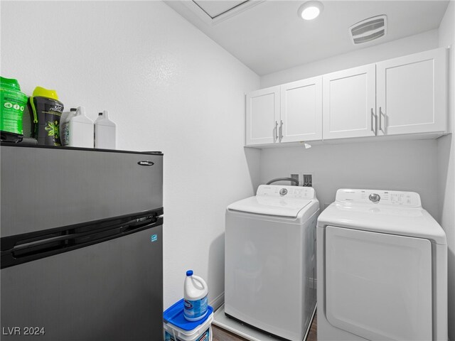 clothes washing area with washer and dryer and cabinets