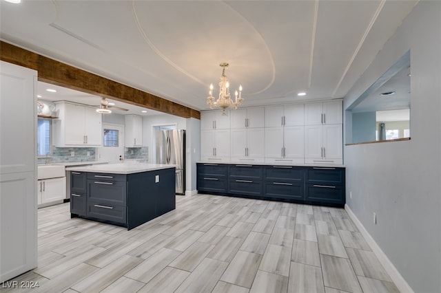 kitchen featuring white cabinetry, a healthy amount of sunlight, a center island, and stainless steel refrigerator