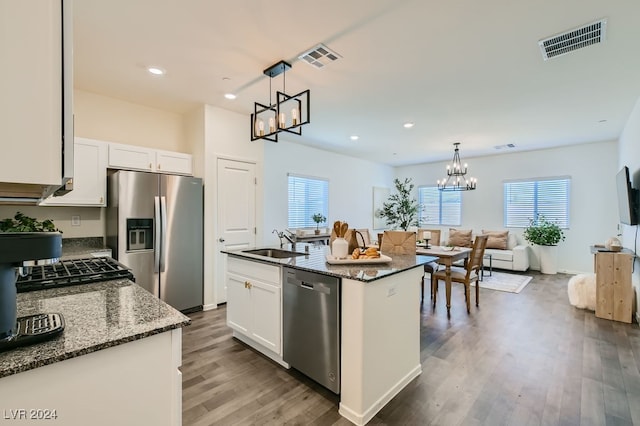 kitchen featuring dark stone countertops, a wealth of natural light, stainless steel appliances, and a center island with sink