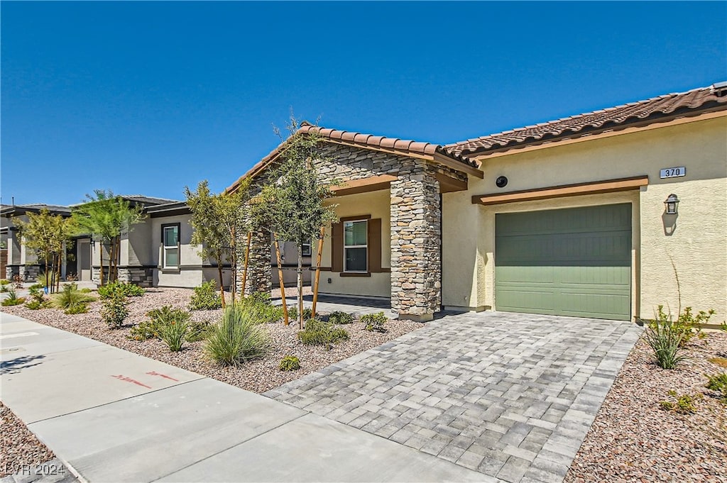 370 Canary Song Dr, Henderson, NV 89011 - view of front facade with stone siding, stucco siding, decorative driveway, and a tile roof