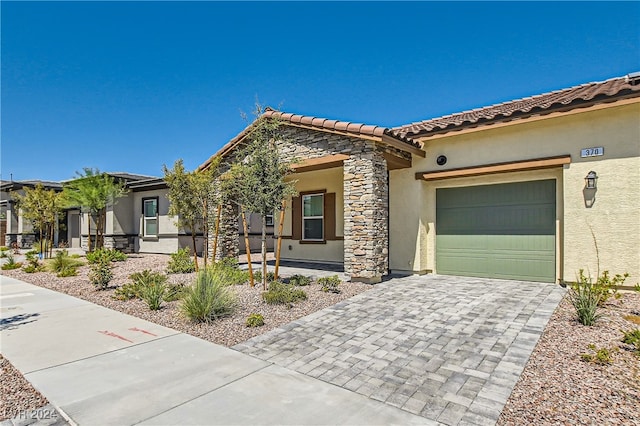 view of front facade with stone siding, stucco siding, decorative driveway, and a tile roof