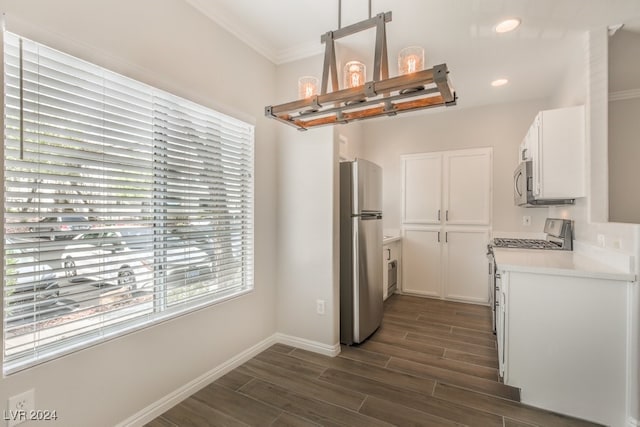 kitchen featuring dark wood-type flooring, appliances with stainless steel finishes, white cabinetry, and ornamental molding