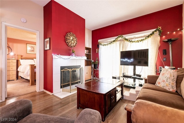 living room featuring a tiled fireplace and wood-type flooring