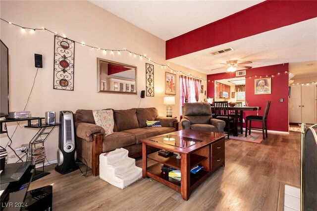 living room featuring a textured ceiling, ceiling fan, and wood-type flooring