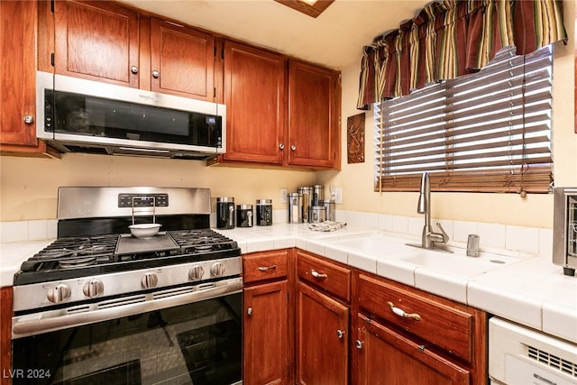 kitchen featuring tile countertops, appliances with stainless steel finishes, and sink