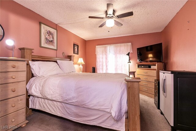 bedroom with a textured ceiling, dark colored carpet, and ceiling fan