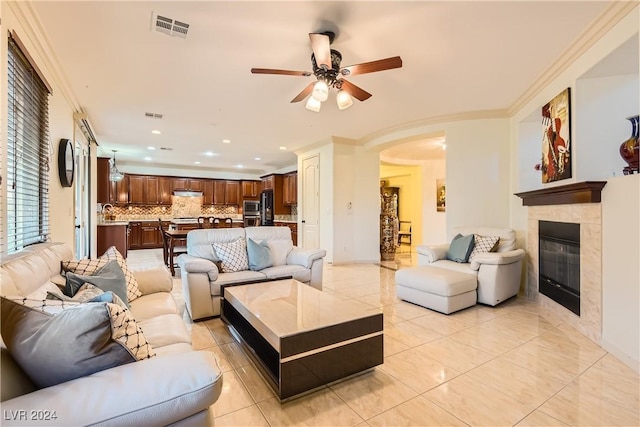 tiled living room featuring a tile fireplace, ceiling fan, and crown molding