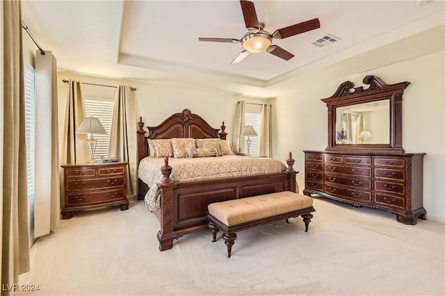 carpeted bedroom with ceiling fan and a raised ceiling