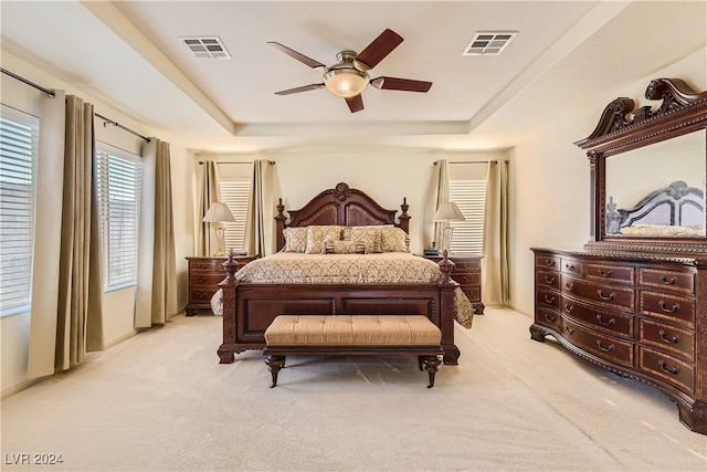 carpeted bedroom featuring a tray ceiling and ceiling fan