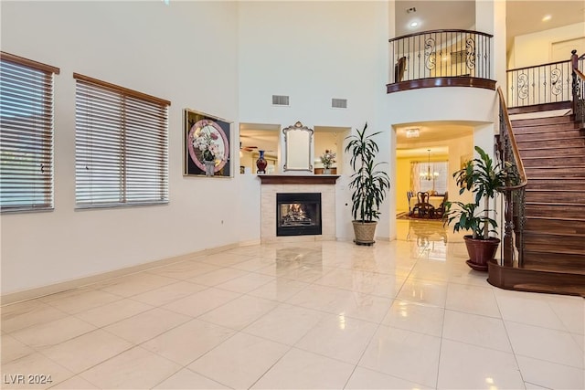 living room with a chandelier, a high ceiling, light tile patterned flooring, and a tiled fireplace