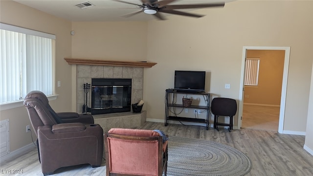 living room featuring a tiled fireplace, hardwood / wood-style flooring, and ceiling fan