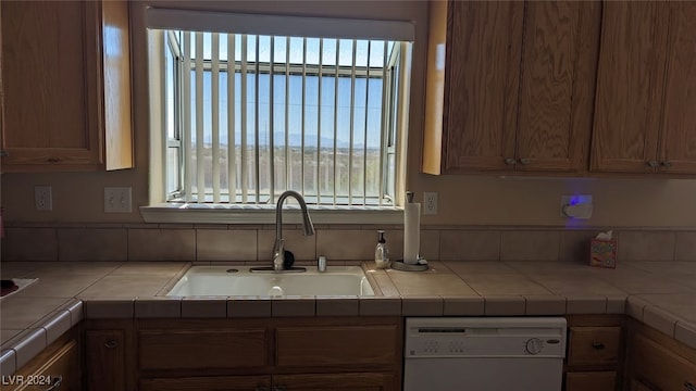 kitchen featuring white dishwasher, sink, and tile counters