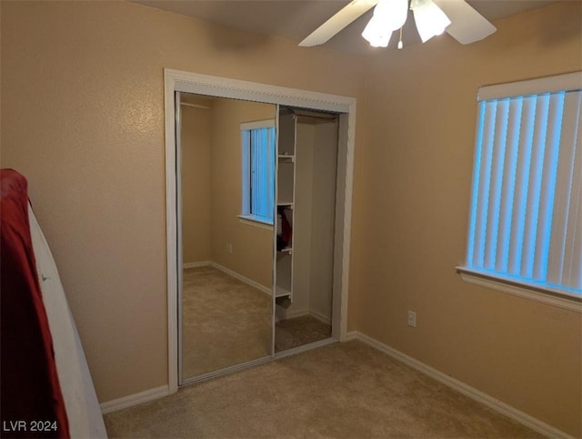 unfurnished bedroom with light colored carpet, a closet, and ceiling fan