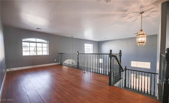 empty room with a chandelier and dark hardwood / wood-style flooring