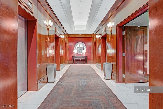 hall with crown molding, wooden walls, and light tile patterned flooring