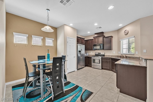 kitchen featuring pendant lighting, stainless steel appliances, sink, light stone countertops, and dark brown cabinetry