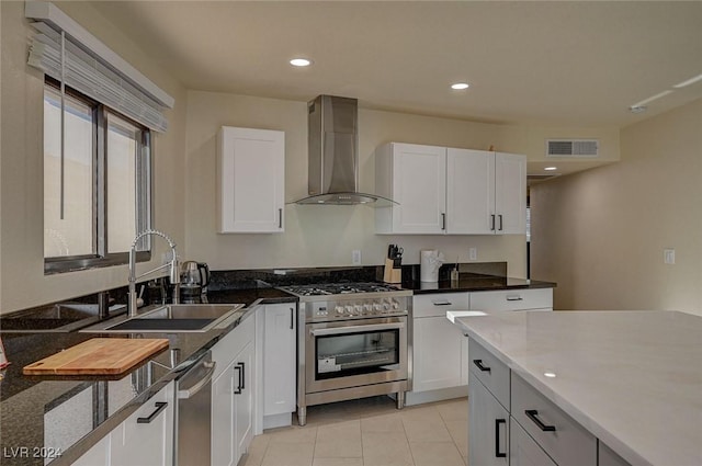 kitchen featuring dark stone counters, white cabinets, sink, wall chimney exhaust hood, and stainless steel appliances