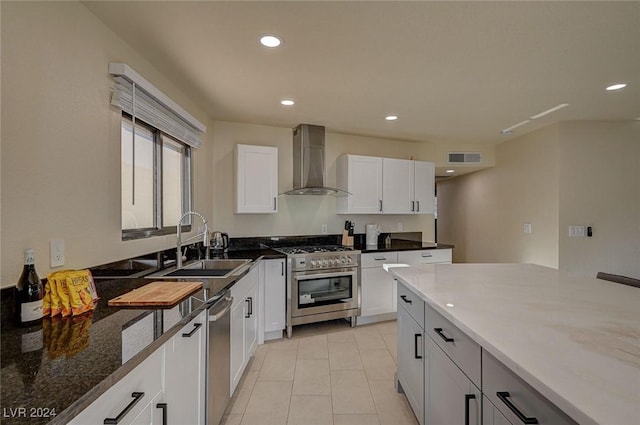 kitchen with stainless steel appliances, sink, wall chimney range hood, stone countertops, and white cabinets