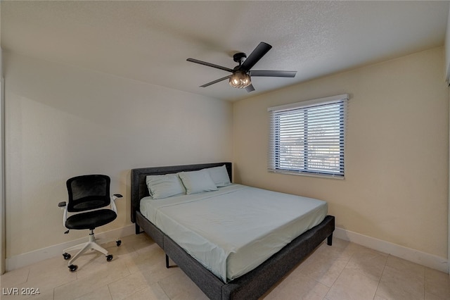 tiled bedroom featuring ceiling fan and a textured ceiling