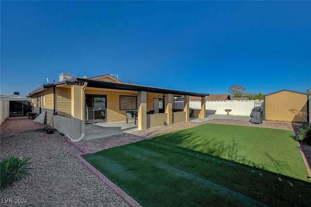 back of property featuring a lawn, a patio area, and a storage shed