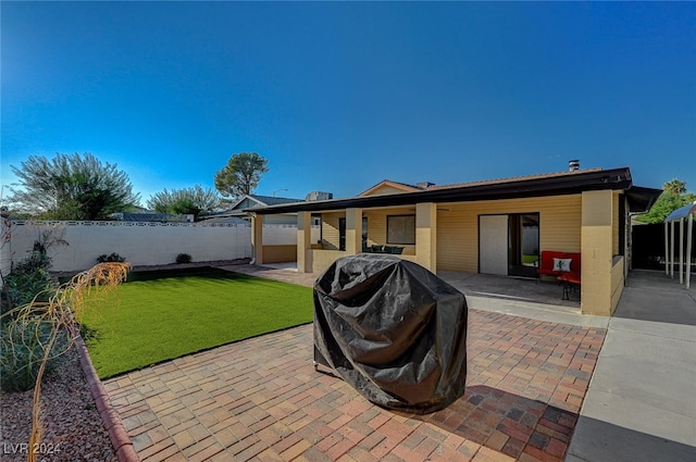 rear view of property featuring a lawn and a patio