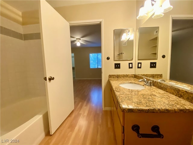 bathroom with tiled shower / bath combo, vanity, hardwood / wood-style floors, and ceiling fan