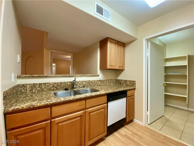 kitchen with white dishwasher, light hardwood / wood-style floors, stone countertops, and sink