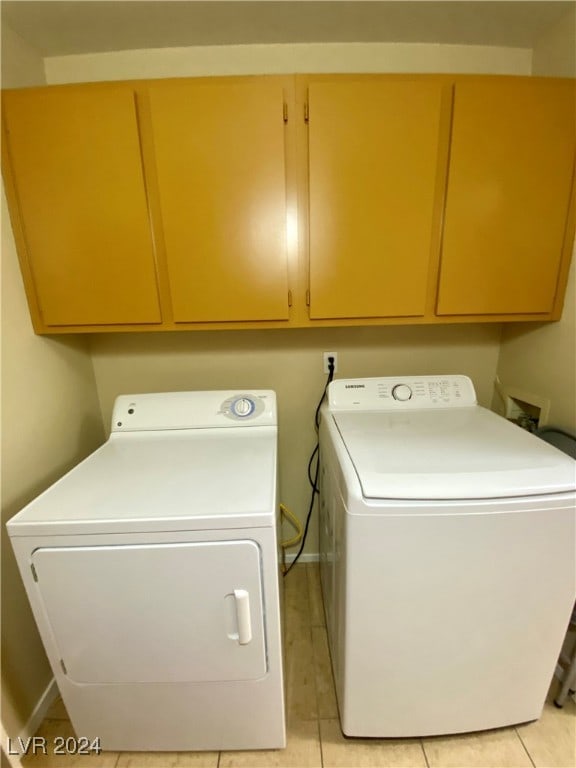 washroom featuring cabinets, separate washer and dryer, and light tile patterned floors