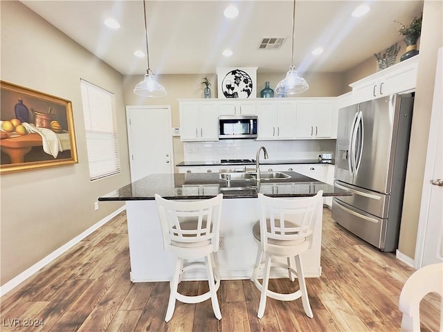 kitchen featuring white cabinetry, a center island with sink, and stainless steel appliances